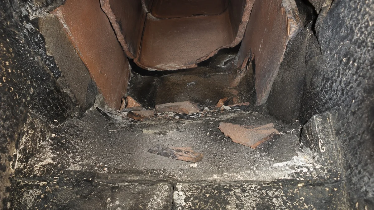 Broken clay flue tile fragments collected on a chimney smoke shelf