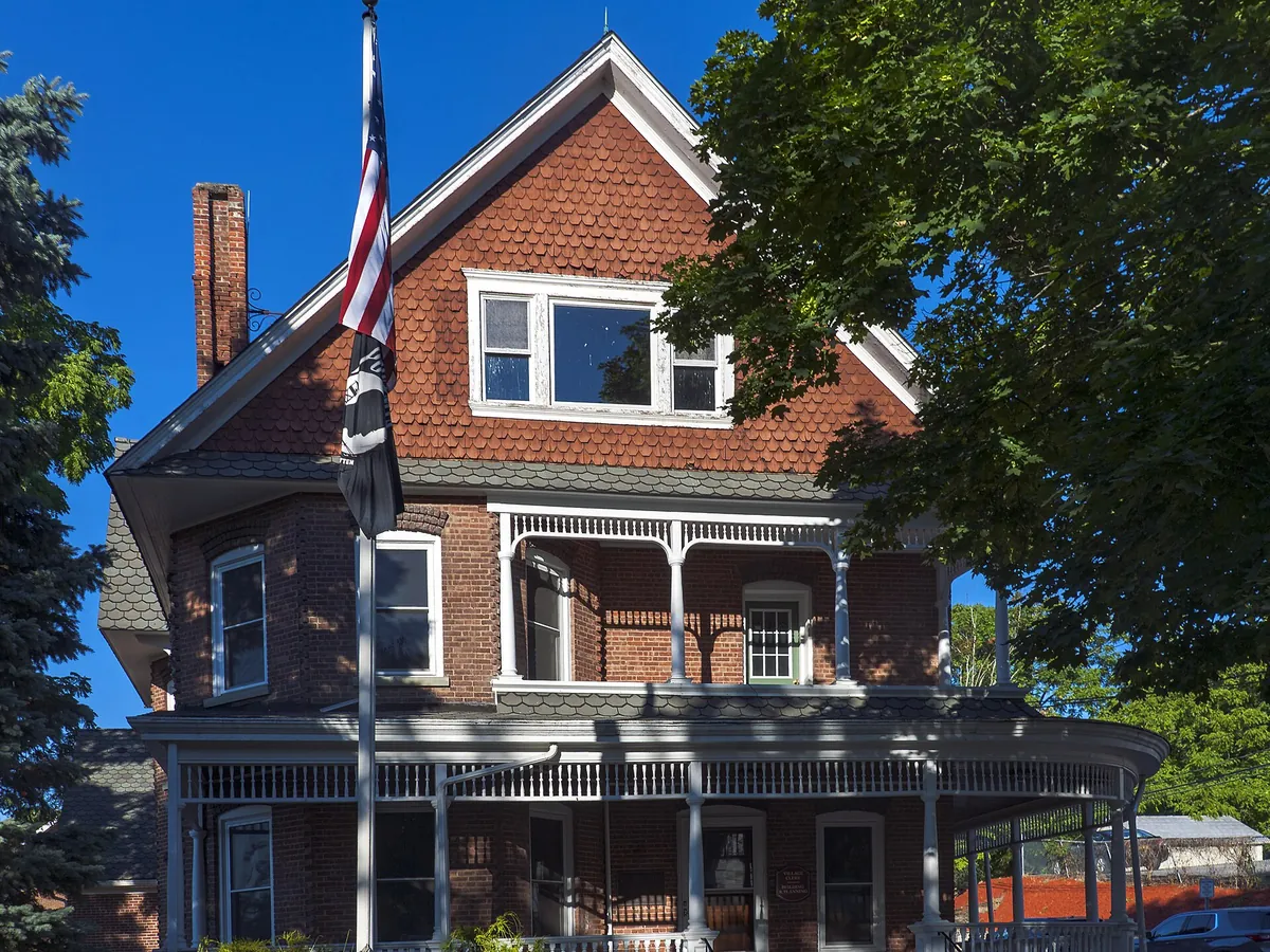 Brick Victorian village hall with a wraparound porch in Florida, New York