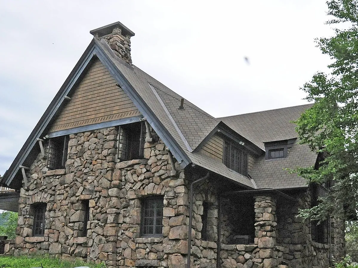 Stone house with a fieldstone chimney on a wooded hillside in Greenwood Lake, New York